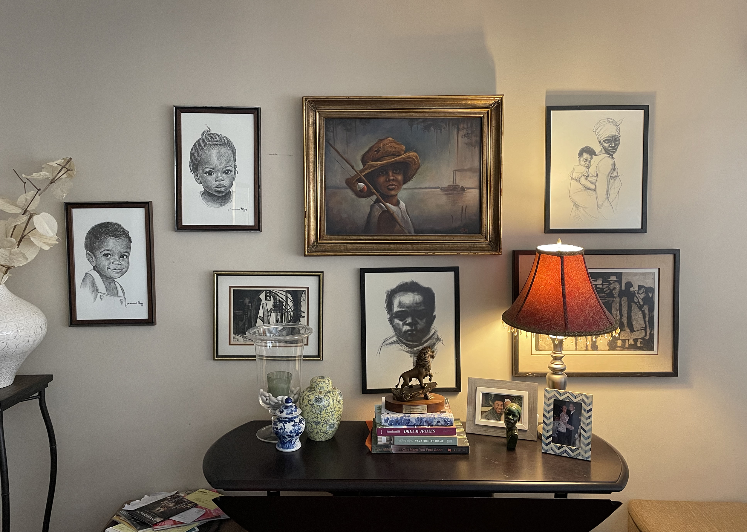 A collage of paintings and drawings of Black people, mostly children, hanging on the wall.